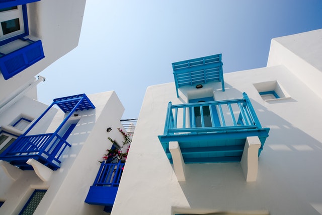 Biela budova s malými balkónmi v modrej farbe