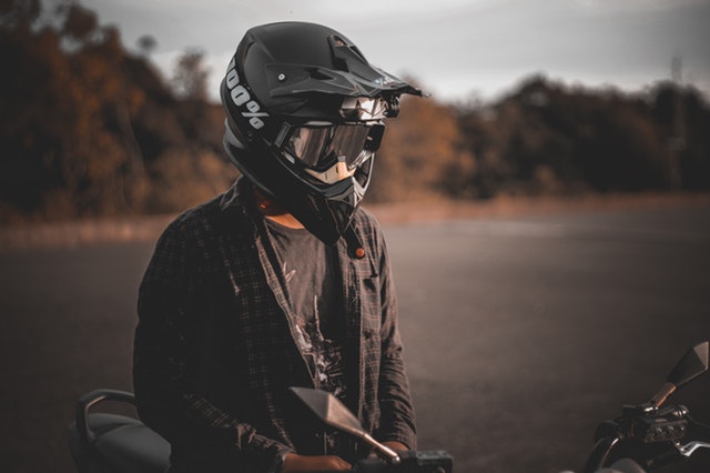 Chlapec v košeli sedí na motorke s prilbou na hlave